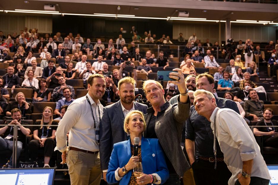 mehrere-speaker-auf-der-k5-konferenzbühne-machen-selfie-im-hintergrund-publikum